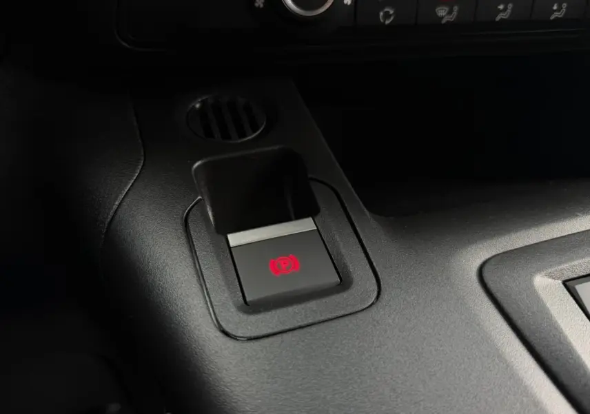 Gros plan sur le bouton de frein de stationnement électrique rouge dans l’habitacle noir du Citroën Berlingo Van XL blanc.