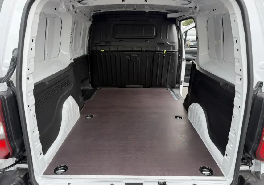 Vue intérieure arrière du Citroën Berlingo blanc Icy avec plancher bois antidérapant et cloison noire.