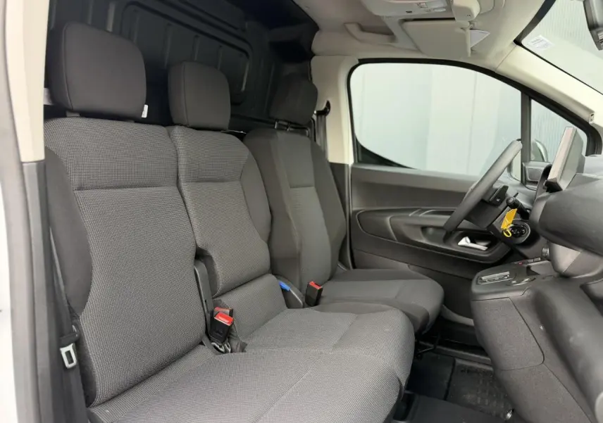 Vue intérieure côté conducteur du Citroën Berlingo Van XL 2026 avec sièges tissu gris et plancher bois visible à l'arrière.