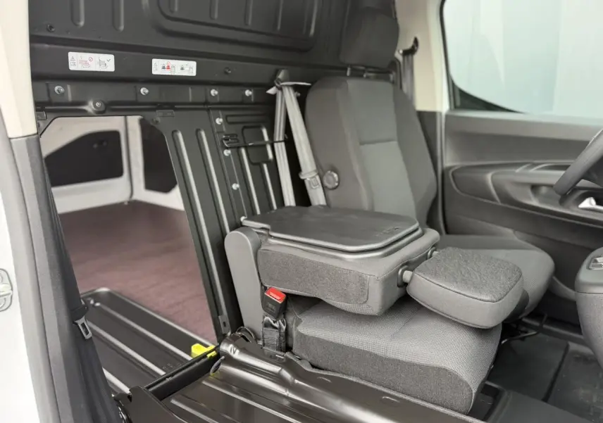 Vue intérieure côté droit du Citroën Berlingo blanc, mettant en valeur le siège passager rabattable et le plancher bois du coffre.