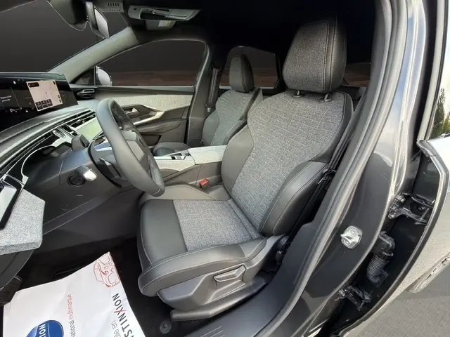 Vue intérieure côté conducteur du Peugeot 3008 gris foncé, sièges tissu et cuir, tableau de bord moderne avec écran tactile.