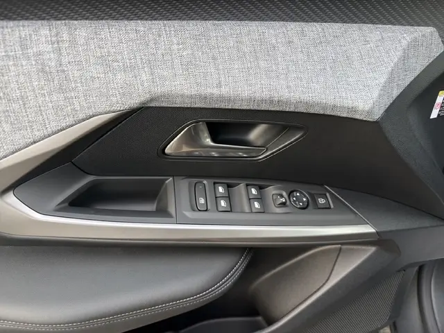 Gros plan sur la porte côté conducteur du Peugeot 3008 gris foncé, avec commandes électriques des vitres et poignée argentée.
