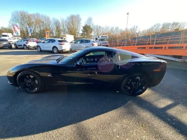 Profil côté gauche d'une Chevrolet Corvette C6 Targa noire de 2005, avec jantes noires et toit amovible visible.