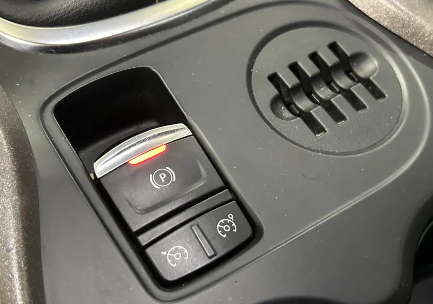 Gros plan sur les commandes de frein à main électronique et régulateur de vitesse du Renault Kadjar gris, version 2015.