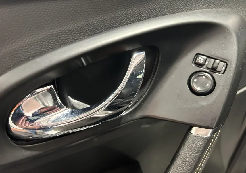 Poignée de porte intérieure chromée côté conducteur du Renault Kadjar gris avec commandes de réglage des rétroviseurs.