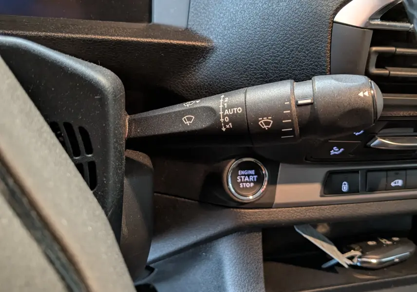 Gros plan sur la commande d’essuie-glace et le bouton start/stop du tableau de bord noir de l’Opel Vivaro Fourgon XL 2024.
