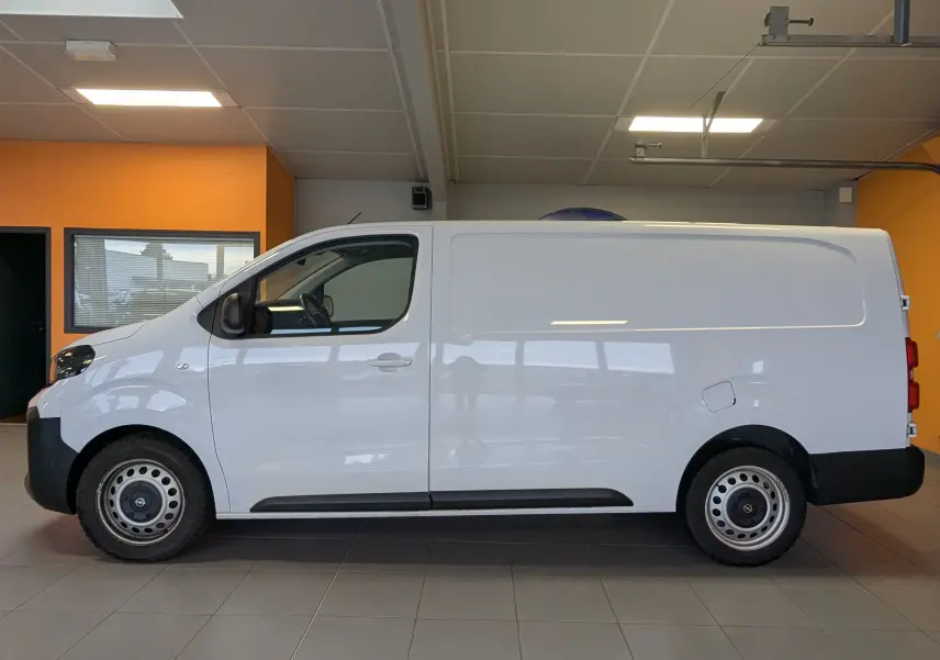 Vue latérale droite d'un Opel Vivaro Fourgon blanc 2024 avec jantes tôles grises et porte coulissante droite en intérieur showroom.