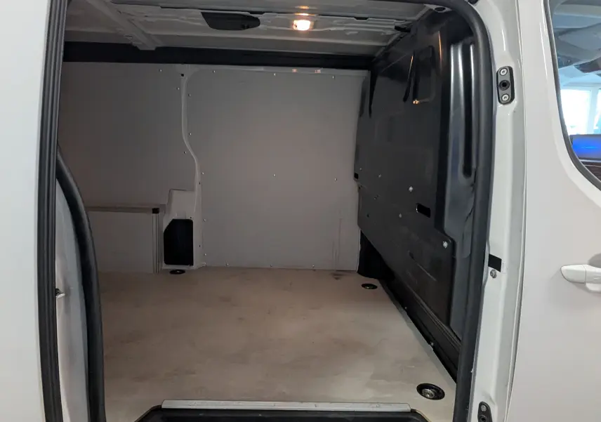 Vue intérieure du compartiment de chargement du fourgon Opel Vivaro XL blanc, avec plancher et parois protégés en bois.