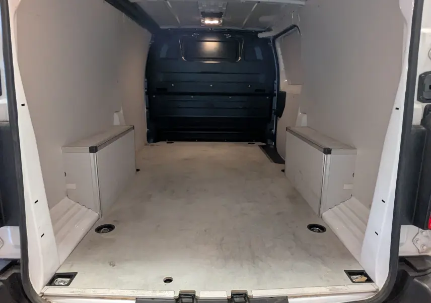 Vue intérieure arrière du fourgon Opel Vivaro XL blanc, montrant l'espace de chargement avec protections latérales en bois.
