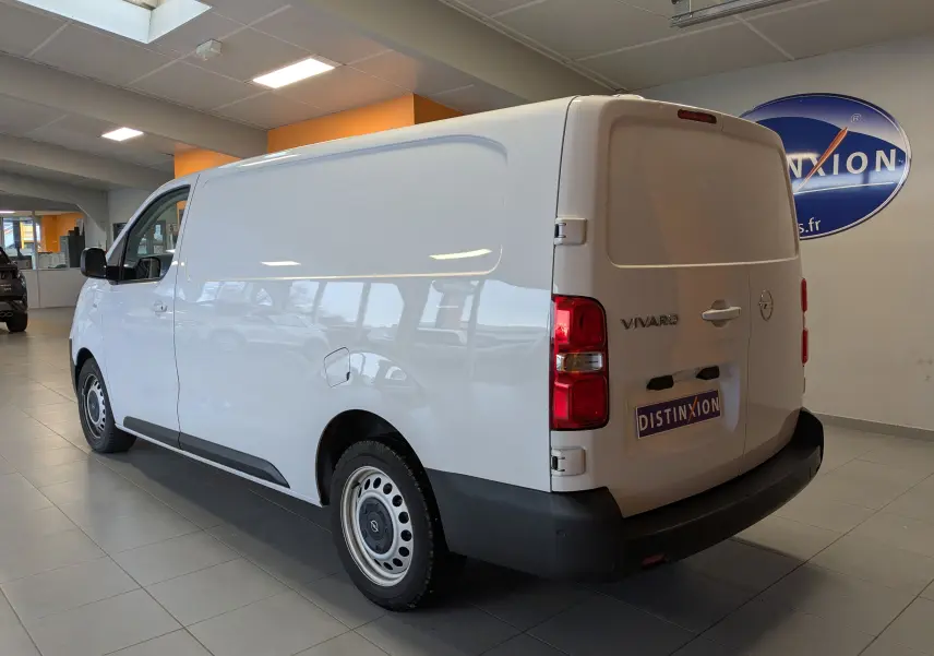 Vue 3/4 arrière droite d’un Opel Vivaro Fourgon blanc 2024 avec jantes tôles grises en showroom.