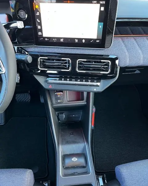 Vue intérieure centrée sur la console centrale de la Renault R5 Techno 2024, avec écran tactile et zone de recharge par induction.