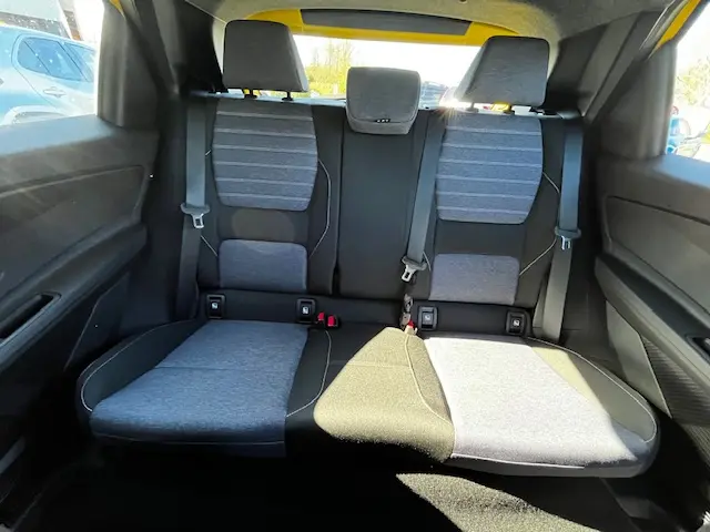 Vue intérieure arrière de la banquette grise et noire de la Renault R5 Techno 150 ch 2024 avec ceintures de sécurité visibles.