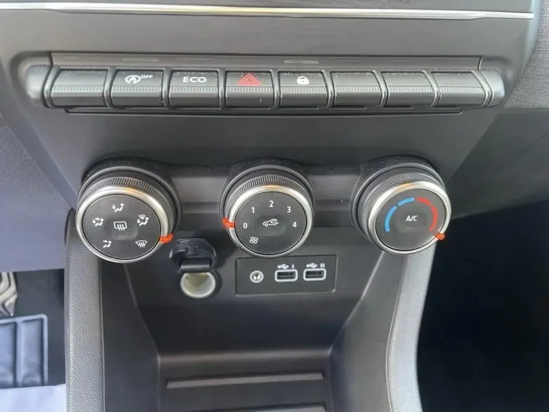 Vue rapprochée des commandes de climatisation et des boutons de fonction sur la console centrale d'une Renault Clio V noire.