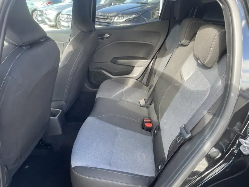 Vue intérieure arrière côté droit de la Renault Clio V noire, montrant les sièges tissu bicolores et les ceintures de sécurité.