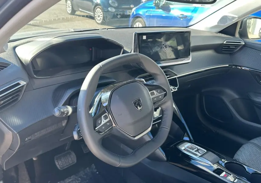 Vue intérieure côté conducteur du Peugeot 208 Hybrid 110 e-DCS6 Allure 2025, volant compact et écran tactile central.