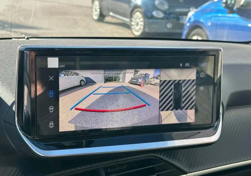 Écran tactile intérieur montrant la caméra de recul et vue 360° du Peugeot 208 gris en stationnement.