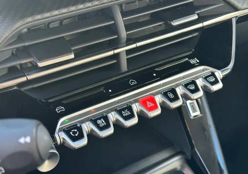 Gros plan sur la console centrale de la Peugeot 208 gris 2025, montrant les commandes tactiles et boutons métalliques.