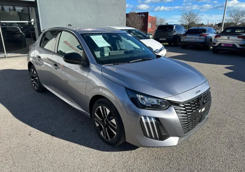 Peugeot 208 Hybrid gris vue 3/4 avant droit, avec calandre noire distinctive et jantes alliage 16 pouces.