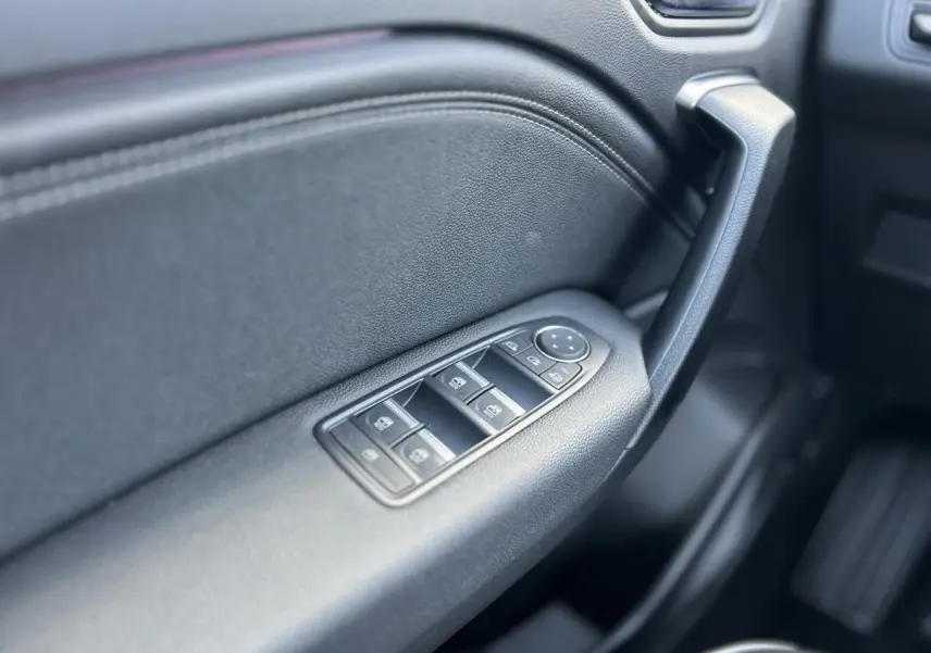 Gros plan sur la commande des vitres électriques côté conducteur du Renault Captur 2024, intérieur noir texturé.
