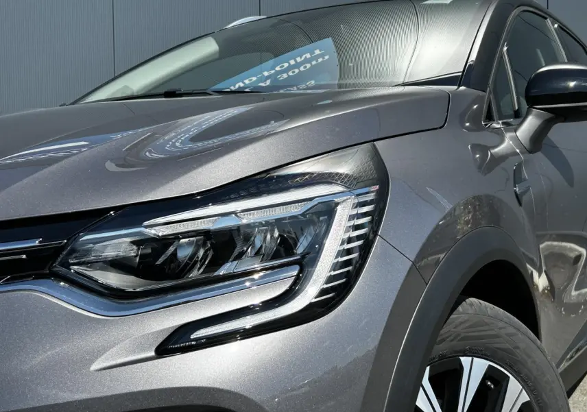 Gros plan sur le phare avant droit du Renault Captur 2024 gris Cassiopée avec jante alliage et rétroviseur noir étoilé.
