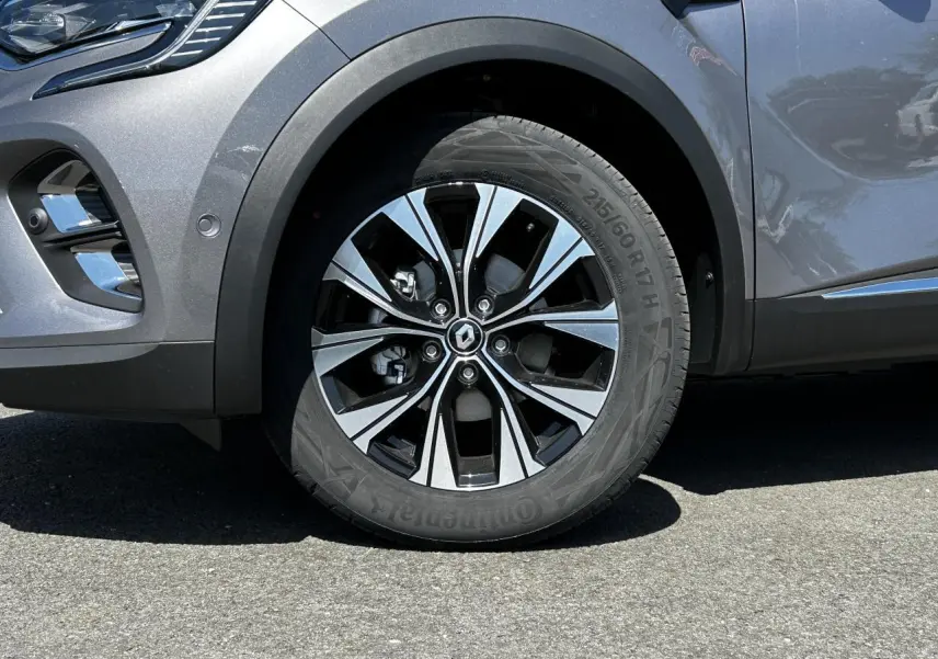 Gros plan sur la roue avant gauche du Renault Captur gris Cassiopée avec jante alliage 17 pouces et partie avant du pare-chocs.