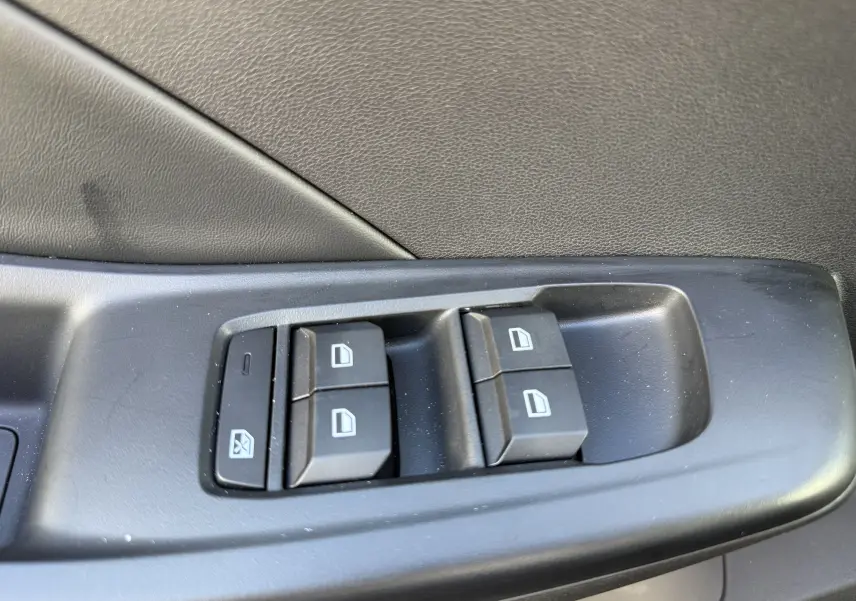 Gros plan sur les commandes de lève-vitres côté conducteur d’une MG3 1.5 HYBRID+ 195 LUXURY noir métal, intérieur noir.