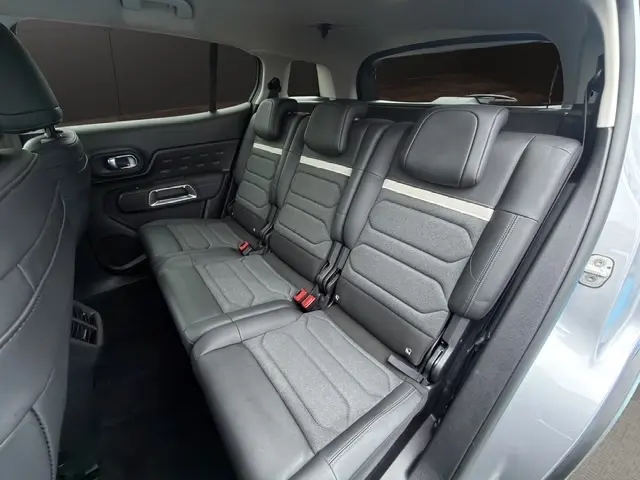 Vue intérieure côté droit sur la banquette arrière trois places en cuir et tissu gris du Citroën C5 Hybride 2024.