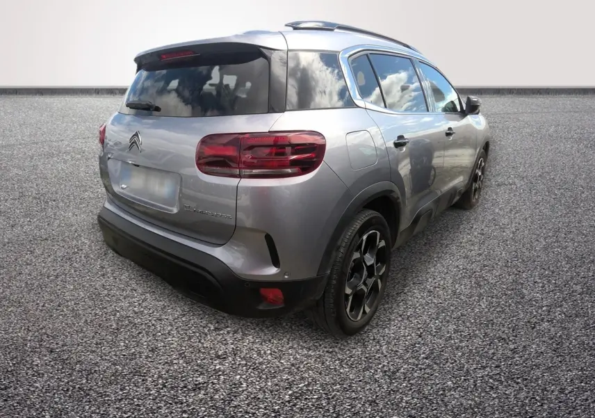 Vue 3/4 arrière droite d'un Citroën C5 gris clair avec toit noir et jantes noires distinctives.