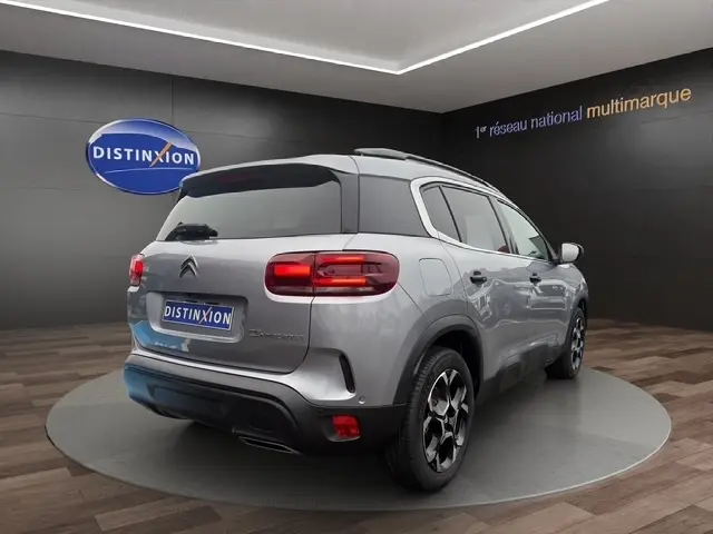 Vue 3/4 arrière droite d'une Citroën C5 Hybride gris clair avec toit noir et jantes distinctives en concession.