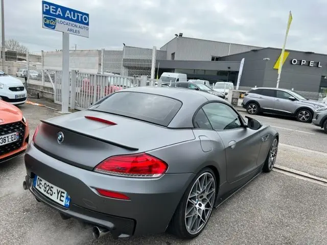BMW Z4 Roadster grise vue 3/4 arrière droit, avec jantes sport et toit rigide fermé, stationnée en extérieur.
