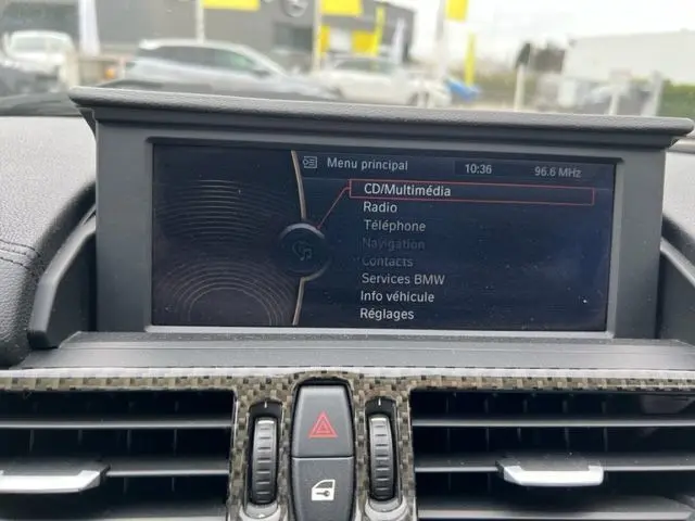 Écran multimédia du tableau de bord d'un BMW Z4 Roadster gris, avec menu principal affiché et commandes centrales visibles.
