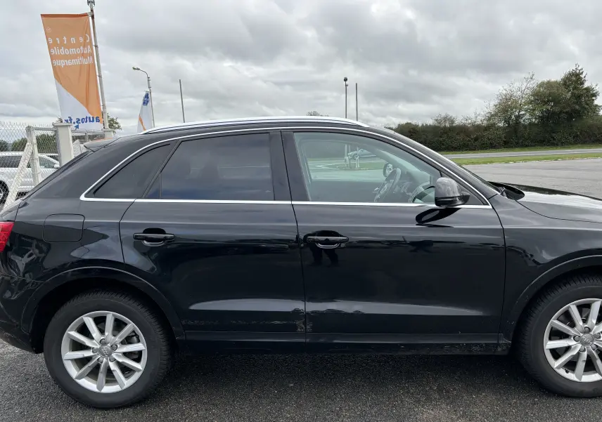 Profil côté gauche d'un Audi Q3 noir de 2014, mettant en valeur ses jantes alliage et ses vitres teintées.