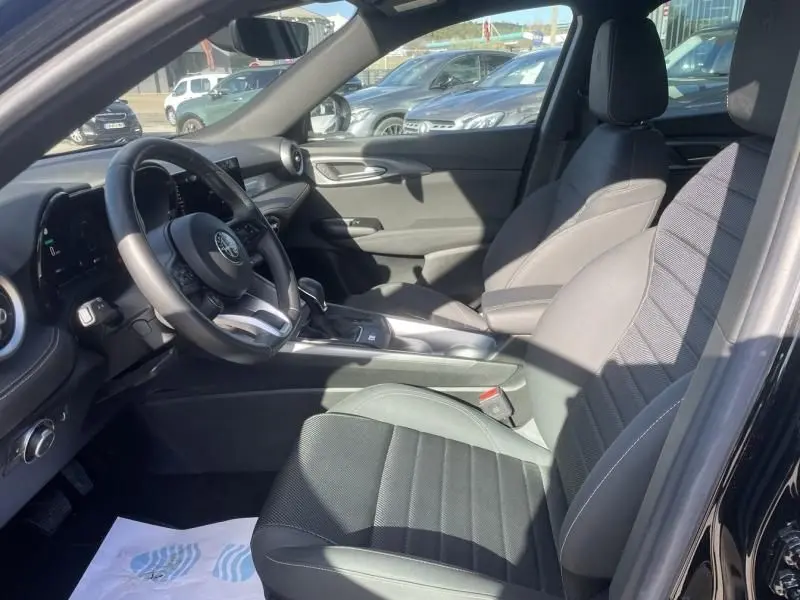 Intérieur côté conducteur de l'Alfa Romeo Tonale noir 2023, montrant sièges en tissu et tableau de bord moderne.