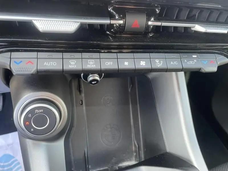 Vue rapprochée de la console centrale noire de l'Alfa Romeo Tonale 2023, avec commandes climatisation et molette de sélection.
