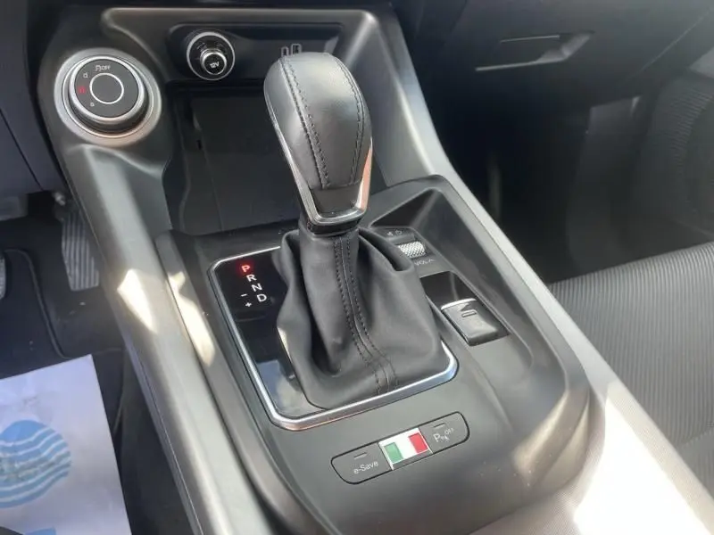 Gros plan sur la console centrale noire de l'Alfa Romeo Tonale 1.3 PHEV 280 CV, avec levier de vitesse automatique et drapeau italien.