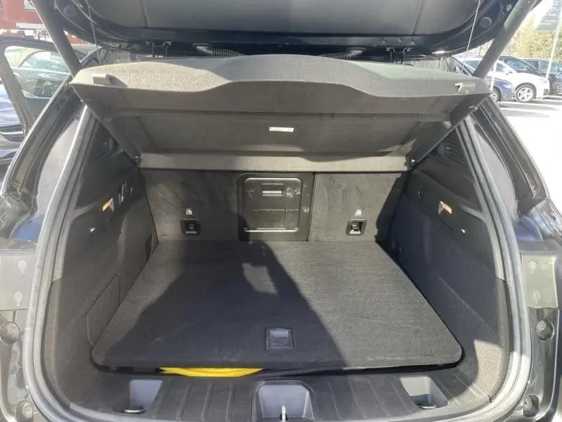 Coffre ouvert vu de l'arrière d'une Alfa Romeo Tonale noire 2023, montrant un espace de chargement propre et bien fini.