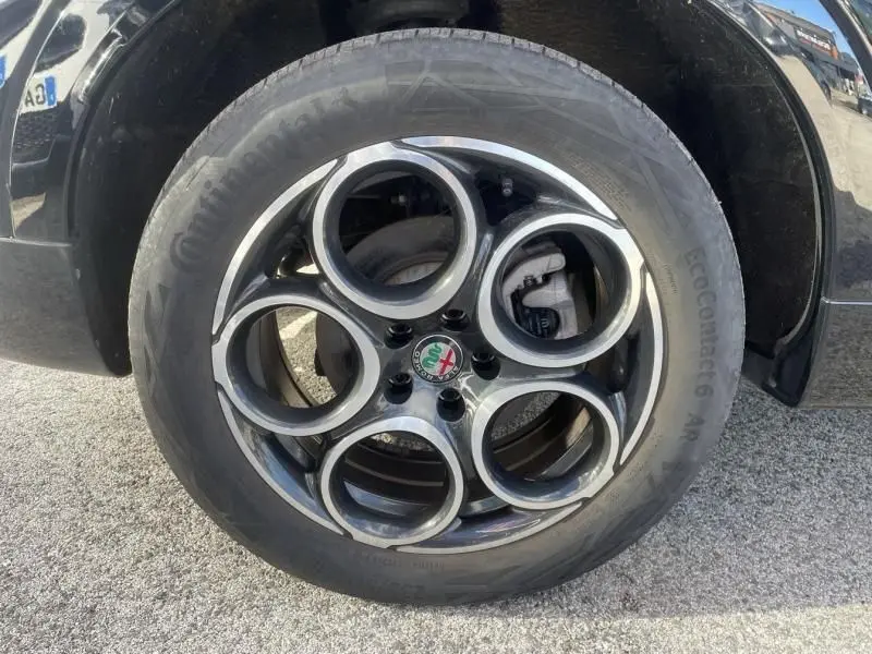 Gros plan sur la jante en alliage noir et argent avec logo Alfa Romeo d’un Alfa Romeo Tonale noir 2023.