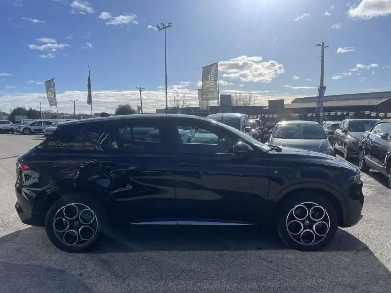 Vue de profil côté gauche d'une Alfa Romeo Tonale noire 2023 avec jantes distinctives à cinq cercles doubles.