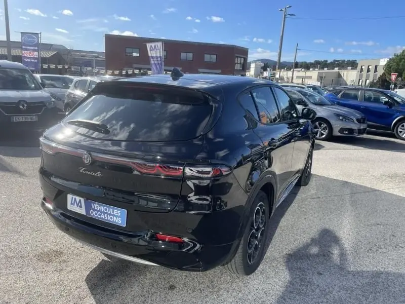 Vue 3/4 arrière droite d'une Alfa Romeo Tonale noire 2023 hybride rechargeable, avec feux arrière distinctifs et jantes sport.