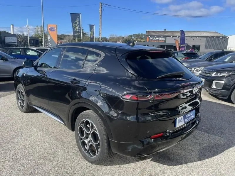 Vue 3/4 arrière droite d'une Alfa Romeo Tonale noire 2023 hybride rechargeable avec jantes distinctives à cinq cercles.