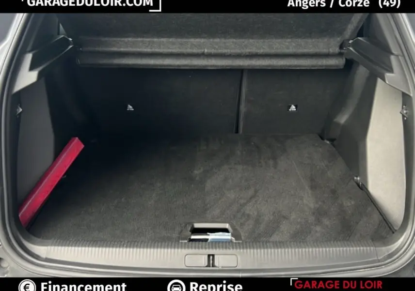 Coffre ouvert d’un Peugeot 2008 Hybrid gris clair, vue arrière montrant l’espace de chargement et un triangle de signalisation rouge sur le côté gauche.