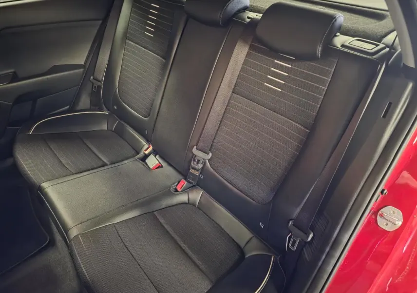 Vue intérieure sur la banquette arrière noire de la KIA RIO rouge, soulignant les ceintures et finitions cuir-tissu.