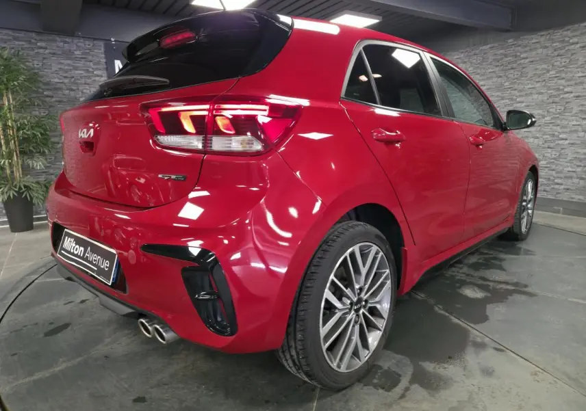 Vue 3/4 arrière droite de la KIA Rio GT Line rouge métallisée avec double sortie d'échappement chromée et jantes alliage 17 pouces.