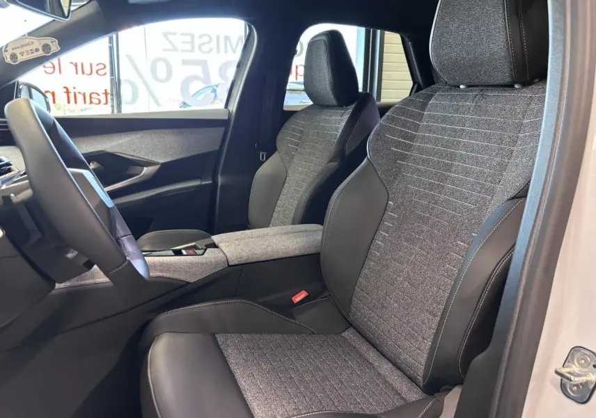 Vue intérieure côté gauche du Peugeot 3008 blanc 2026, sièges tissu gris et cuir noir avec accoudoir central.