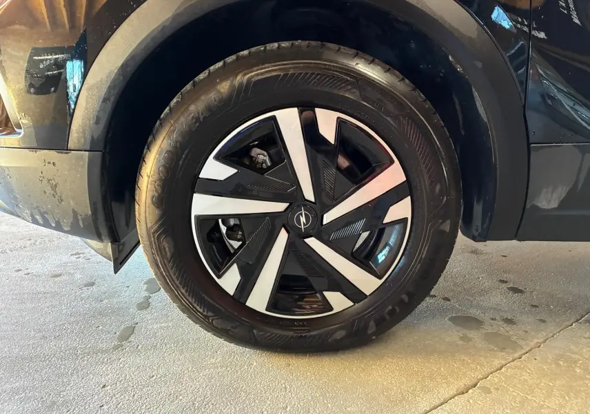 Gros plan sur la roue avant gauche noire d'un Opel Mokka 2025, jante alliage au design géométrique bicolore.