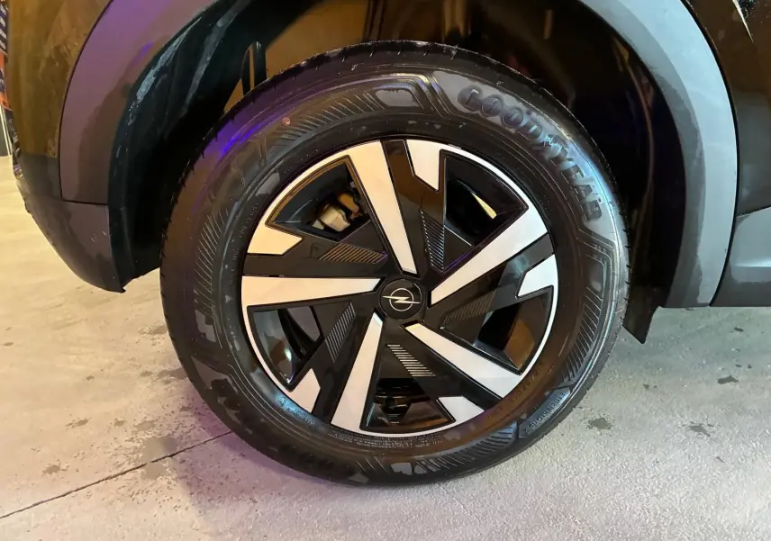 Gros plan sur la roue avant droite noire de l’Opel Mokka 1.2 Turbo 145 Edition avec jante alliage bicolore et pneu Goodyear.