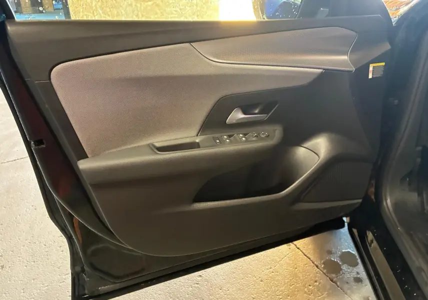 Vue intérieure de la porte avant gauche noire de l’Opel Mokka 1.2 Turbo 145 Edition avec commandes de vitres et poignée intégrée.