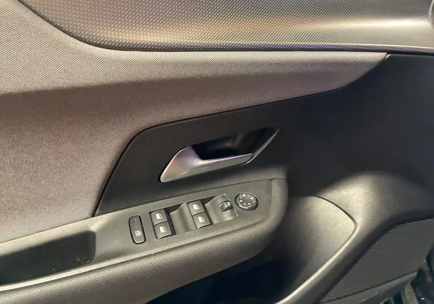 Détail de la porte intérieure côté conducteur de l’Opel Mokka 2025 noire, avec commandes des vitres et poignée argentée.