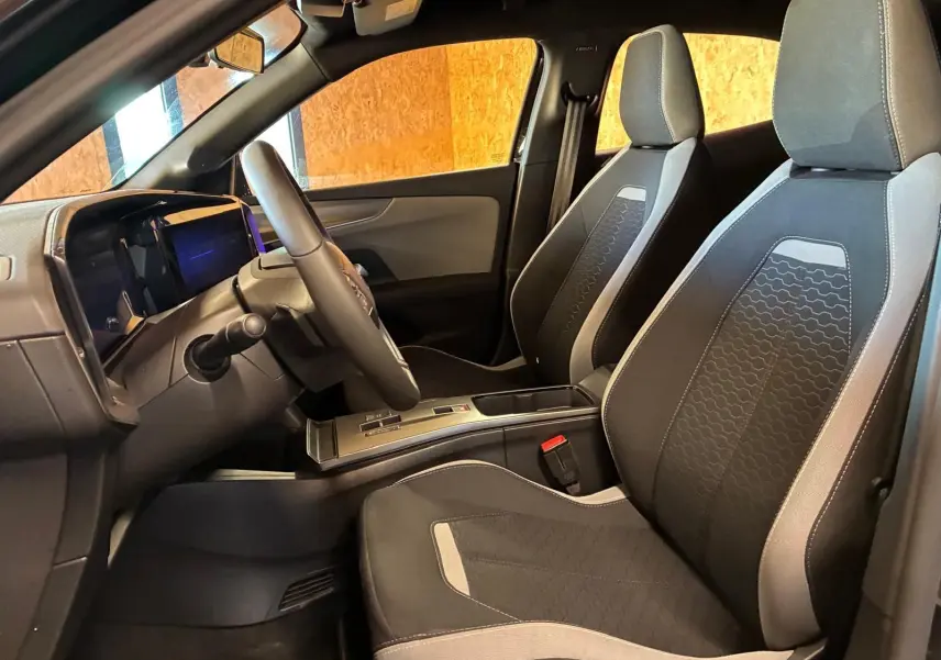 Vue intérieure côté conducteur de l’Opel Mokka 1.2 Turbo 145 Edition 2025, sièges tissu noir avec surpiqûres grises.
