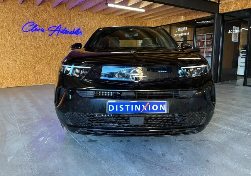 Vue frontale d'un Opel Mokka 1.2 Turbo 145 Edition noir brillant, avec calandre moderne et logo Opel éclairé.